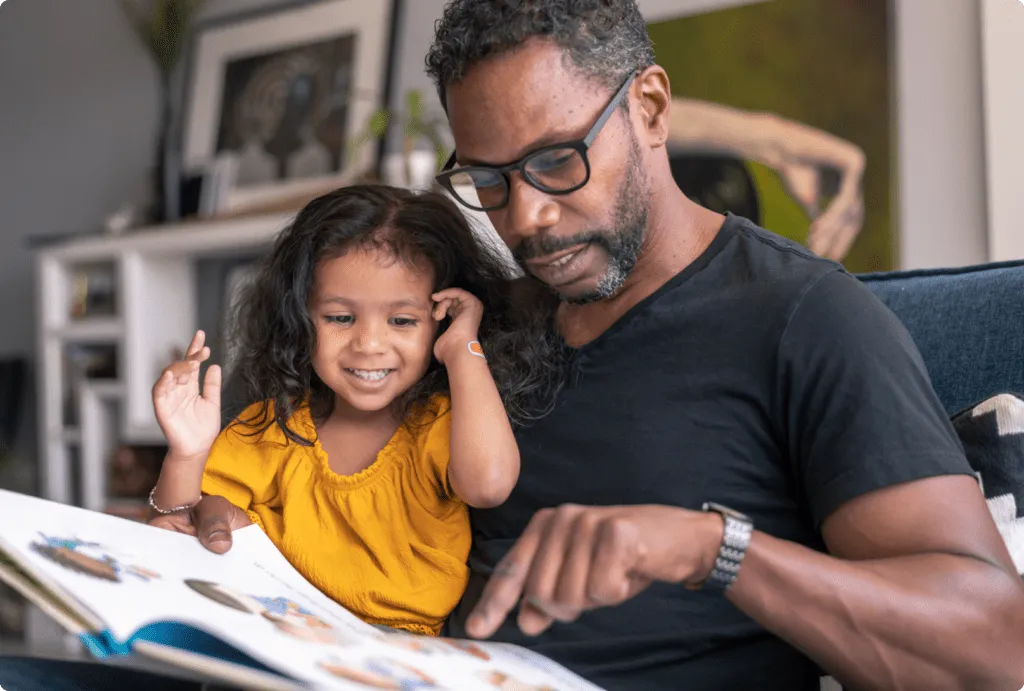 father reading to daughter at home