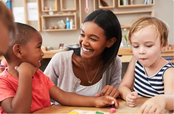 teacher in classroom with happy children playing with wooden blocks