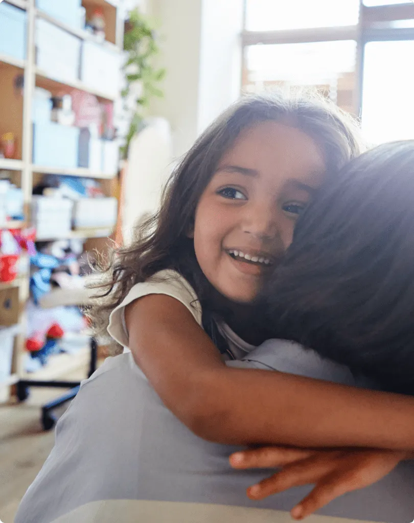 child happily hugging an adult in a classroom