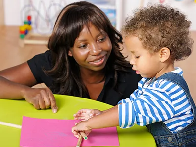 Black teacher teaching a black toddler learning to write