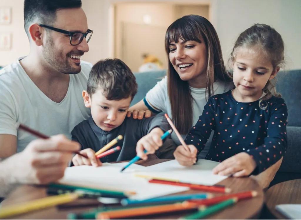 two children at home with parents drawing