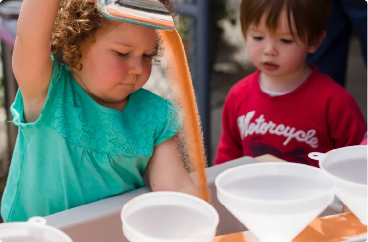 two young children enjoying a tabletop sandbox