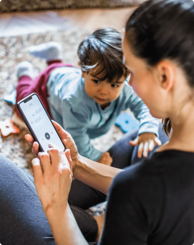 mother at home using a mobile phone while child overlooking