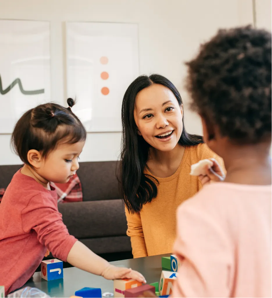 Home Child Care smiling adult children playing with blocks