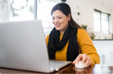 woman at laptop smiling in her house