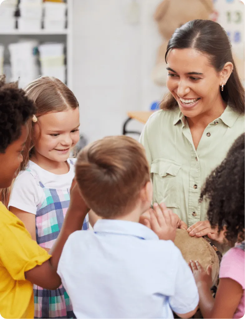 smiling teacher with children playing a percussion instrument