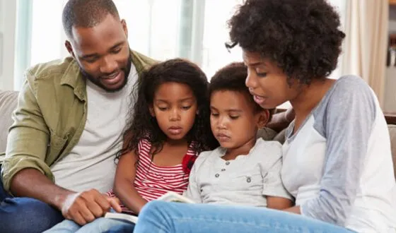 mother and father with two children reading at home